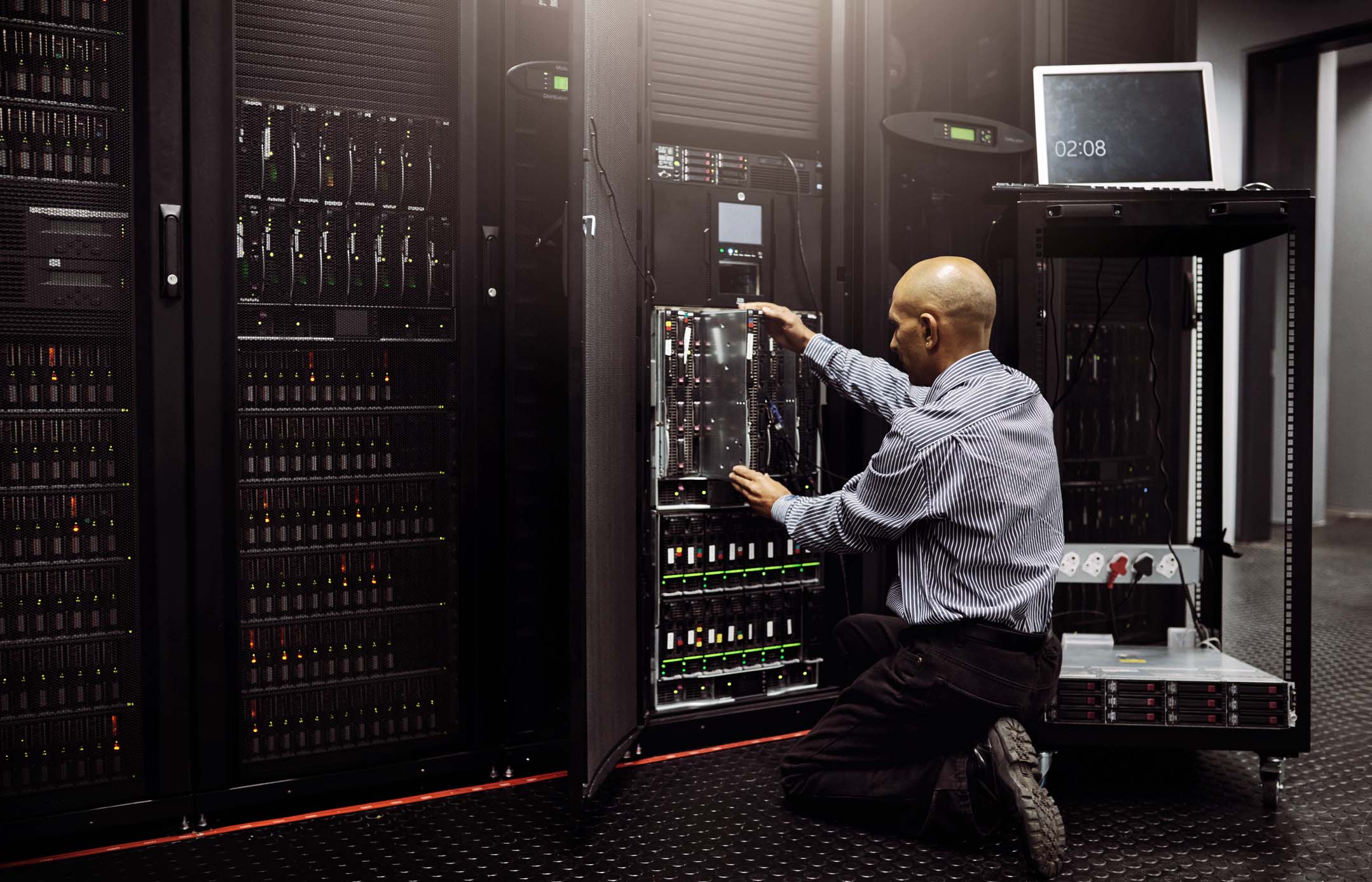 Rearview shot of an IT technician repairing a computer in a data center